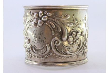 Argola de guardanapo em prata com motivos florais relevados envolvendo cartela para monograma.